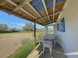 un patio avec une table et des chaises sous un toit en bois dans l'établissement Cabane de Gardian 6 pers, nature, animaux admis, parking - FR-1-475-186, à Saintes-Maries-de-la-Mer 3 autres photos