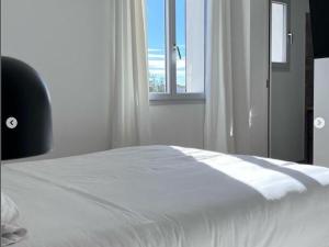 białe łóżko w pokoju z oknem w obiekcie Charmante maison neuve à Saintes-Maries-de-la-Mer pour 4 personnes - FR-1-475-189 w Saintes-Maries-de-la-Mer