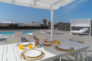 a table with plates of food and drinks on a patio at Vv Villa Secretos de Yaiza 1 by Hh - private pool & BBQ in Yaiza
