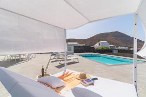a patio with a pool and a white umbrella at Vv Villa Secretos de Yaiza 1 by Hh - private pool & BBQ in Yaiza