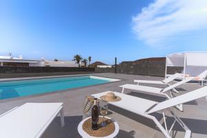 a villa with a swimming pool and two white chairs at Vv Villa Secretos de Yaiza 1 by Hh - private pool & BBQ in Yaiza