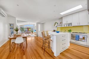 a kitchen with white cabinets and a table and chairs at Jan Juc Beach Home in Torquay