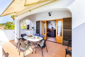 Un patio con mesa y sillas y una cocina. en Villa Ponent, en Son Bou