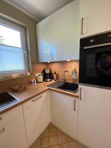 a kitchen with white cabinets and a sink and a window at Meerzeit in Zingst