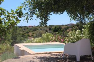 a swimming pool with a chair in a garden at BeGuest Casas de Taipa in Lagoa