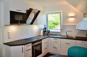 une cuisine avec des armoires blanches, un évier et une fenêtre dans l'établissement Am Alten Leuchtfeuer, à Eckernförde