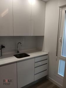 eine Küche mit weißen Schränken und einer Spüle in der Unterkunft Puerta de Hierro Apartments in Madrid