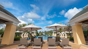 eine Terrasse mit Stühlen und Sonnenschirmen neben einem Pool in der Unterkunft Phuket Graceland Resort and Spa in Patong Beach