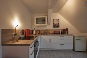 a kitchen with white cabinets and a tv on the wall at Ferienwohnung im Pfarrhaus Kölzow in Kölzow
