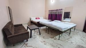 a room with two beds and a couch and a chair at LD Guest House, Ayodhya in Ayodhya
