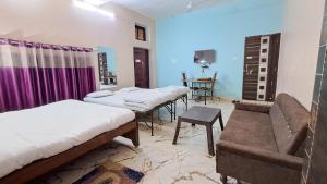 a room with three beds and a couch and a table at LD Guest House, Ayodhya in Ayodhya