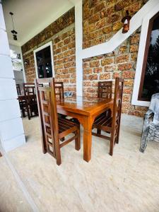 a wooden table with chairs and a brick wall at Nelumbo Villa 42 - oasis of relaxations in Uragasmanhandiya +21 photos