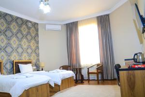 Una habitación de hotel con dos camas y una ventana. en ELANI Hotel, en Samarkand