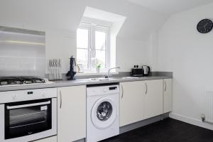 Una cocina blanca con lavadora y secadora. en K Suites - Shetland Court, en Bridgwater