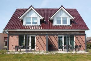 StickHaus 4711 rechtes Haus in Tossens的一座红色屋顶和窗户的房子