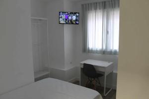sypialnia z łóżkiem, biurkiem i telewizorem w obiekcie Hostal royal begoña w Madrycie