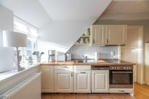 a kitchen with white cabinets and a sink at Landhaus am Meer - Whg 8 Westerley in Utersum