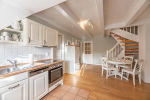 a kitchen with white cabinets and a table and a staircase at Landhaus am Meer - Whg 8 Westerley in Utersum