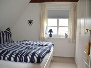 a bedroom with a bed with a blue and white stripes at Haus Bornholm Whg Anemone in Nieblum +2 photos