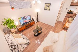 ein Wohnzimmer mit Couch und Fernseher in der Unterkunft 駅4分新築92平米車庫付一戸建丸貸し和風寝室広いリビング上野秋葉原東京品川直通 in Tokio