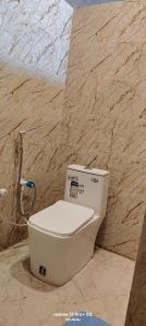 a white toilet in a bathroom with a marble wall at A&R home stay & food in Faizābād +12 photos