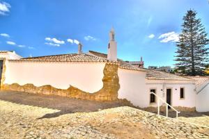 a church with a stone wall next to a building at BeGuest Alcantarilha Family Home in Alcantarilha