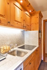 una cucina con lavello e mobili in legno di Chesa Alvra - Celerina a Celerina Altre 37 foto