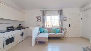 a white kitchen with a chair and a washing machine at La Siesta Perfecta in Villacosta