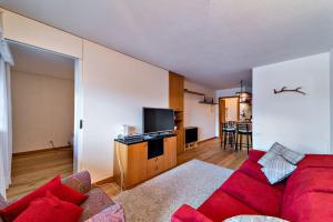 a living room with a red couch and a tv at Chesa Dmuretta - Madulain in Madulain