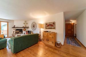a living room with a green couch and a table at Chesa Gravulaina - Madulain in Madulain +12 photos