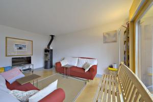 a living room with a red couch and a table at Chesa Ladina - Zuoz in Zuoz