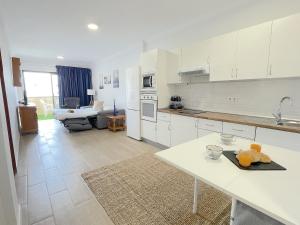 a kitchen with white cabinets and a living room at Agaete Park 609 by Villas Rivero in Playa del Ingles
