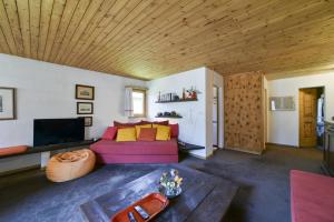 a living room with a purple couch and a wooden ceiling at Chesa Bursella - Madulain in Madulain