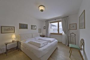 una camera da letto con un letto bianco e una finestra di Chesa Charots - Celerina a Celerina
