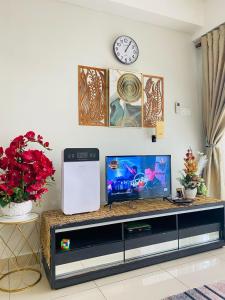 a living room with a tv and a clock on the wall at EM Suite Homestay Dperdana Apartment Kota Bharu in Kota Bharu