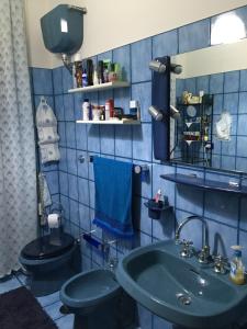a blue tiled bathroom with a toilet and a sink at A casa di mamma in Rieti