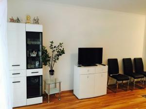 a living room with a tv on a white cabinet and chairs at Apartment near Villa Turgenev in Baden-Baden