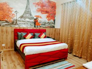 グルガオンにあるHotel Tulipの赤いベッドとエッフェル塔の絵画が備わるベッドルーム1室