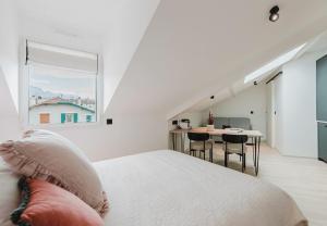 a white bedroom with a bed and a table at Appart Hotel Neostelia in Annecy