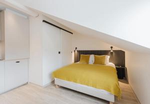 a bedroom with a yellow bed in a white room at Appart Hotel Neostelia in Annecy