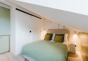 a bedroom with a bed with green sheets and yellow pillows at Appart Hotel Neostelia in Annecy