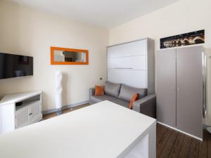 ein weißes Wohnzimmer mit einem Sofa und einem TV in der Unterkunft Studio triangle d'Or in Bordeaux