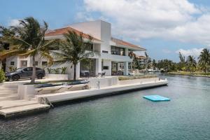 a house on a river with a boat in the water at Luxury villa 5 bdr oceanfront 5 min walk to cenote in Puerto Aventuras