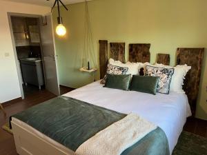 a bedroom with a large white bed with green pillows at Assossego House - Gerês in Geres