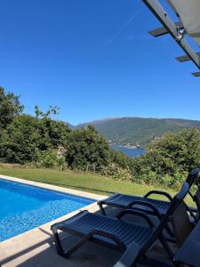 a swimming pool with two lawn chairs next to it at Assossego House - Gerês in Geres