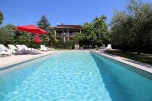 a swimming pool with a red umbrella and chairs and a house at Melisa 6 in Poreč