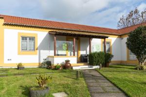 a yellow and white house with a yard at Quinta São José da Relva in Ponta Delgada