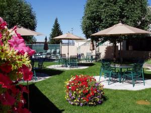 un giardino con sedie, tavoli, ombrelloni e fiori di Broadway Inn Conference Center a Missoula