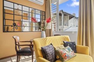 a living room with a yellow couch and a table and a window at Tropical Chic Immeuble Le Botanik in Fort-de-France