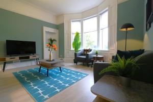 a living room with a tv and a blue rug at Signature - St James House in Abbotsinch